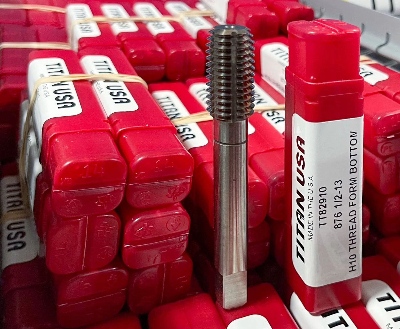 titan usa thread forming tool on stack of red product packaging containers