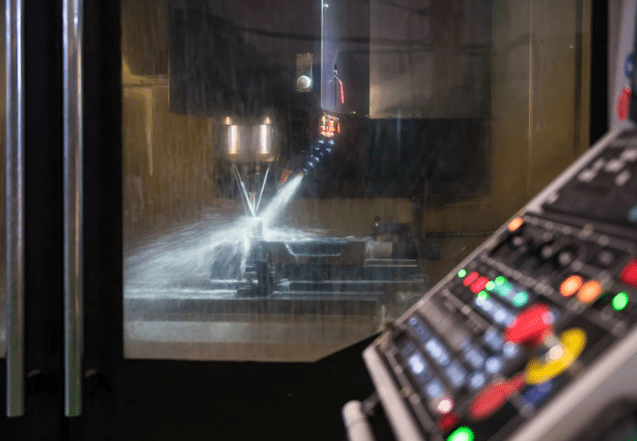 cnc machine looking through glass window focusing on a tool in the cut with external coolant spraying the workpiece